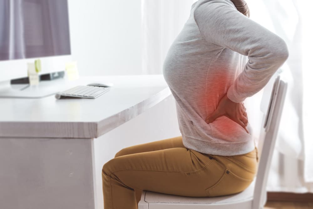Ból pleców - pacjentka na krześle przy biurku