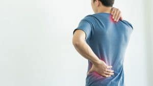 ból przeciążeniowy - lumbago - mężczyzna w szarej koszulce z chorymi plecami