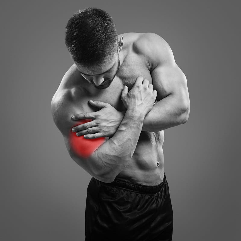 Mężczyzna trzymający się za bicepsa z powodu bólu